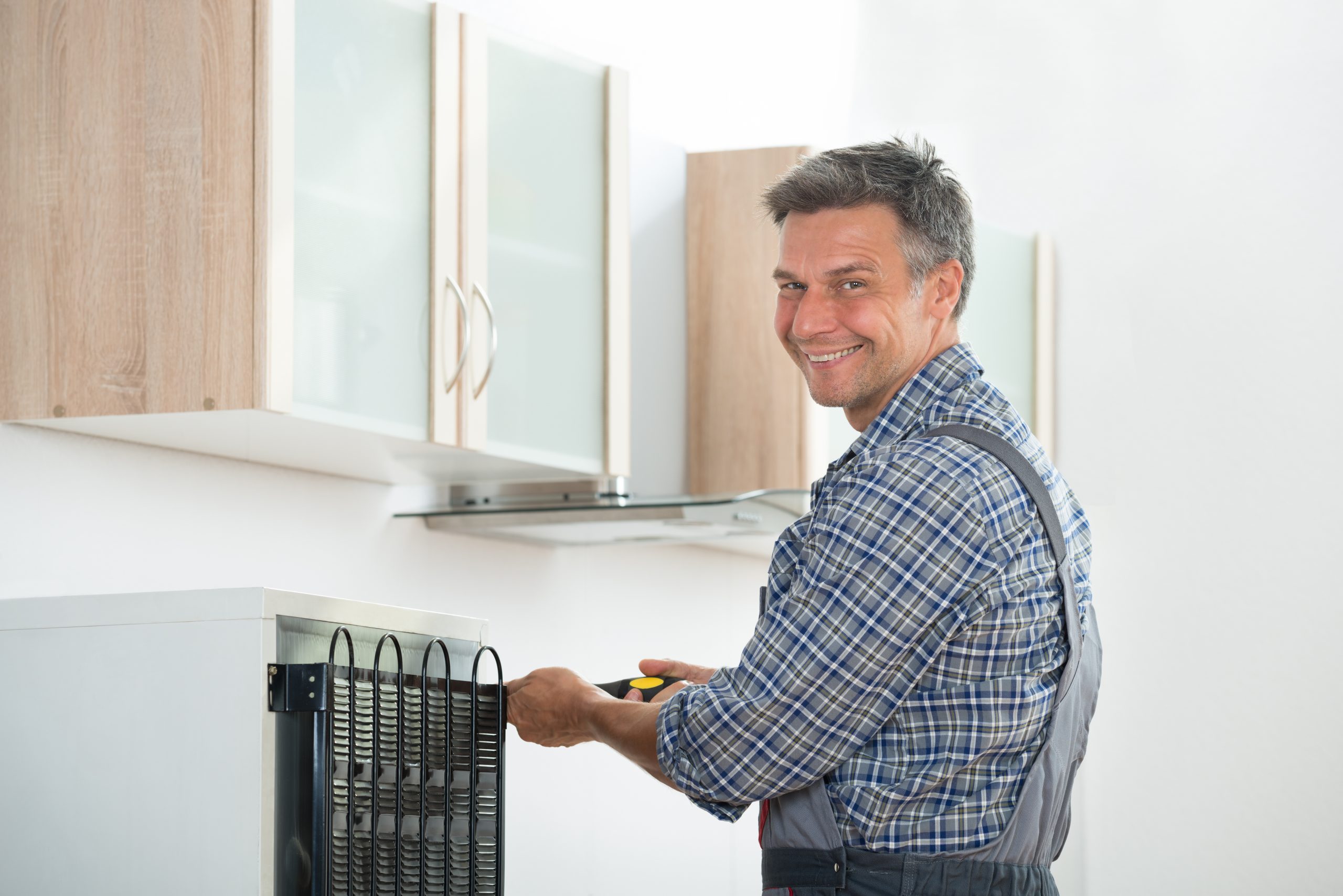 Happy Handyman Repairing Refrigerator At Home